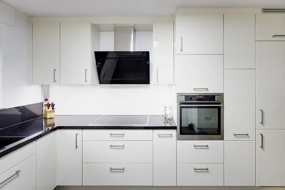 Moderne Küche mit weißen Schränken und schwarzen Arbeitsplatten.