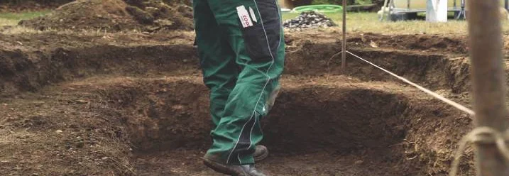 Person gräbt mit einem Spaten ein Loch in die Erde.