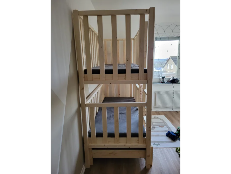 Ein Hochbett aus hellem Holz mit zwei übereinander liegenden Betten.