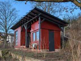 Ein rotes Gartenhaus aus Holz, das sich im Bau befindet.