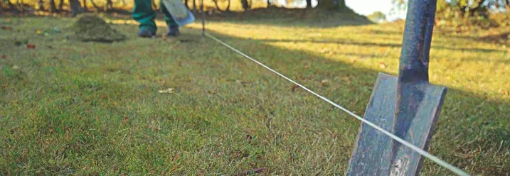Eine gespannte Richtschnur im Garten, im Vordergrund steckt ein Spaten in der Erde
