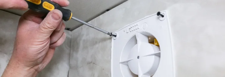 Person montiert Lüfter mit Schraubendreher.