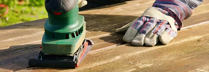 Person schleift Holztisch mit Schleifgerät