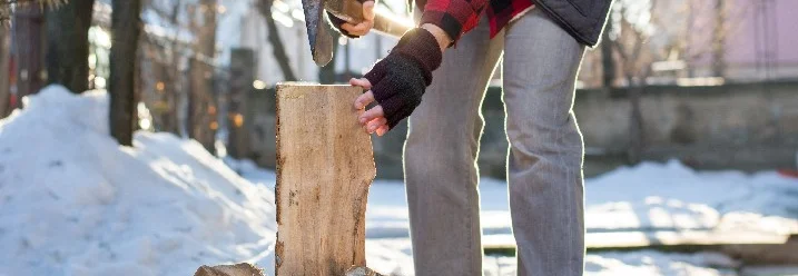 Person hackt Holz mit Axt