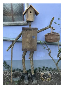 Vogelscheuche aus Holz mit Vogelhaus als Kopf.