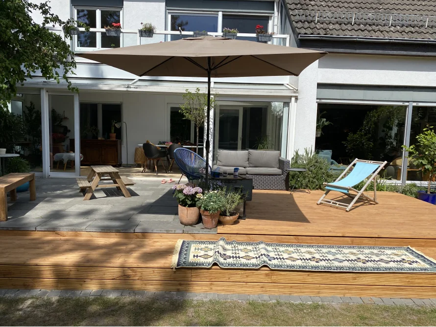 Holzterrasse mit Sonnenschirm und Gartenmöbeln