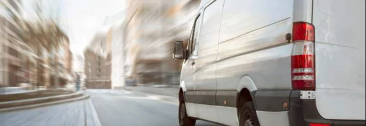 Weißer Transporter fährt durch die Stadt.