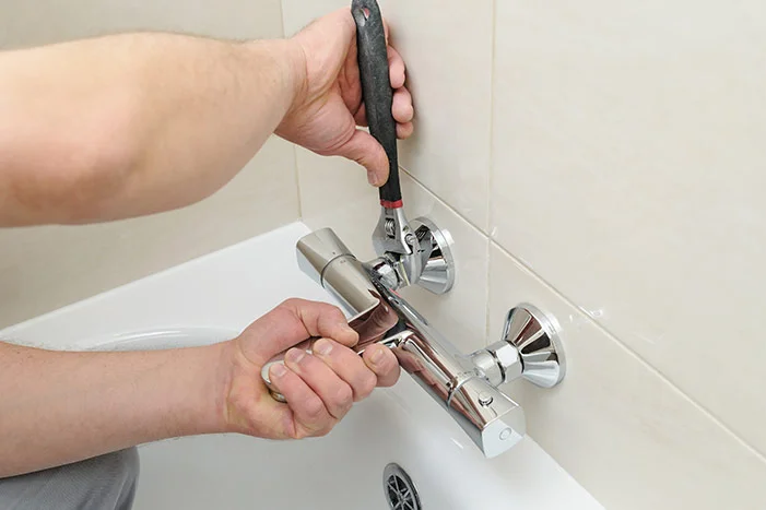 Person montiert Wasserhahn mit Schraubenschlüssel.