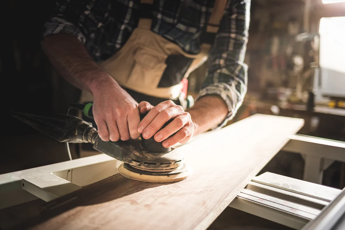 Person schleift Holz mit einem Schwingschleifer