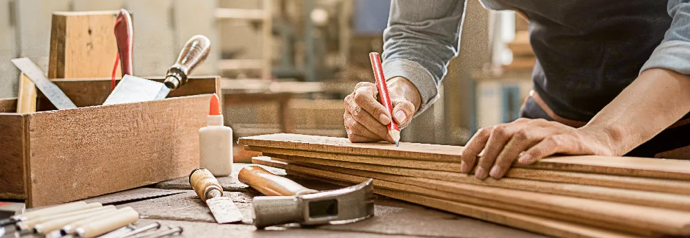 Person zeichnet auf Holz mit Bleistift