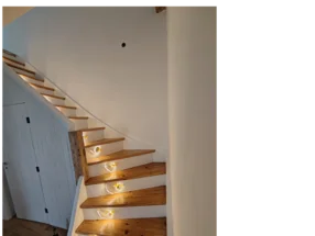 Beleuchtete Holztreppe mit weißem Geländer