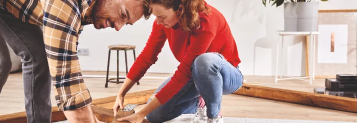 Zwei Personen bauen ein Holzgerüst mit einem Winkel zusammen.