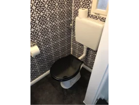 Toilette mit schwarz-weiß gemusterter Wand