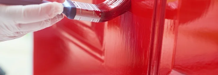 Hand streicht Tür rot mit Pinsel