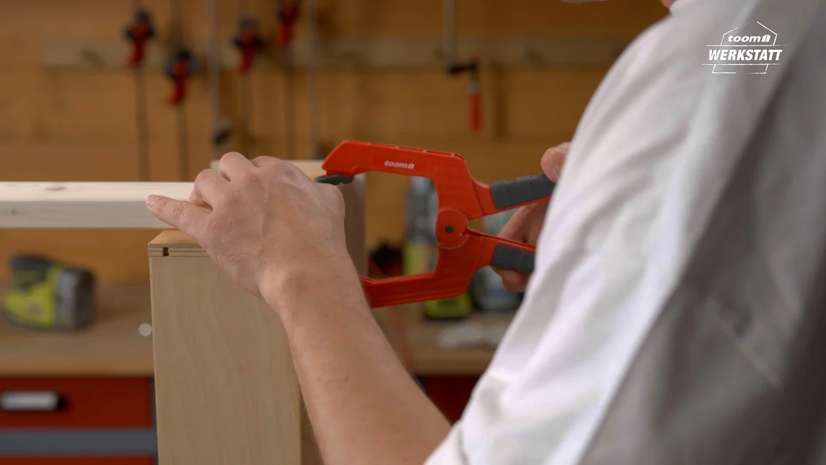 Person befestigt Holz mit Schraubzwinge