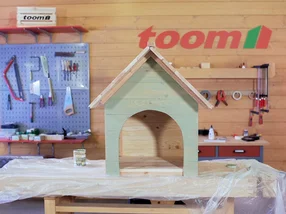 Eine Holz-Hundehütte steht in einer Werkstatt