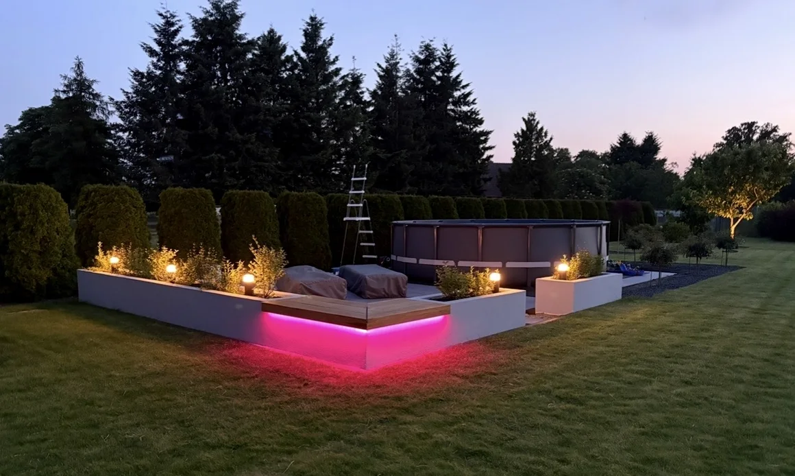 Garten mit Pool, Leiter und pink beleuchteter Terrasse bei Dämmerung.