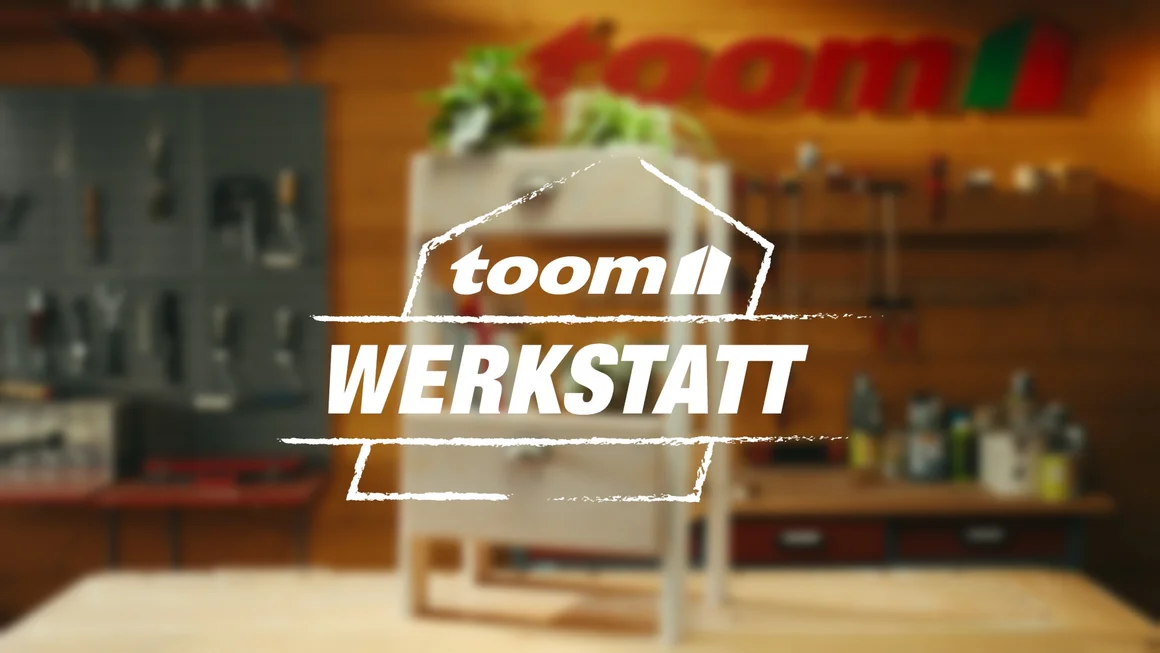 Unscharfer Hintergrund: Werkstatt mit Werkzeug. Davor sieht man das toom Werkstatt Logo