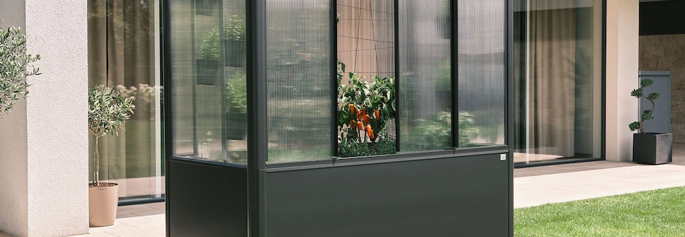 Ein Biohort Design-Gewächshaus steht in einem Garten