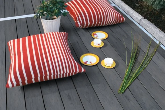 Graue Holzterrasse mit zwei roten Kissen