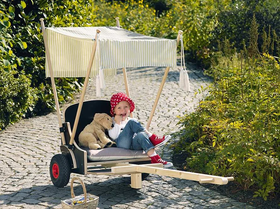 Kind sitzt in kleinem Holzlastenrad