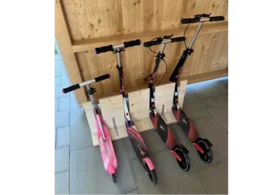 Vier Tretroller stehen an einer Holzkonstruktion