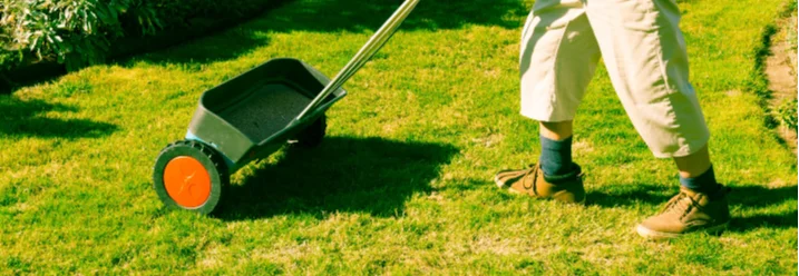 Person verwendet einen Streuwagen im Garten