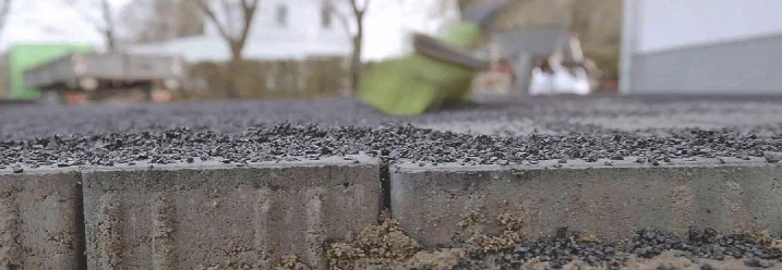 Splitt wird mit Hilfe eines Besens auf Pflastersteinen verteilt