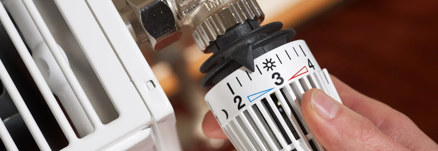 Person dreht am Heizungsthermostat