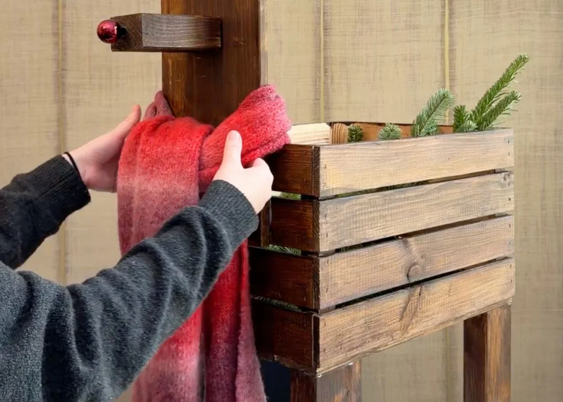 Eine Person dekoriert eine Holzgarderobe mit einem roten Schal.