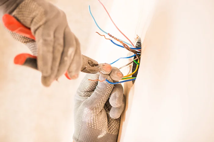 Handwerk Person greift mit Zange Kabel