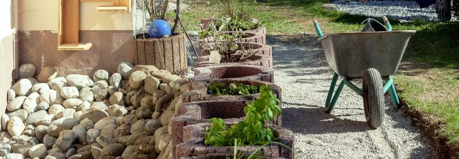 Eine Schubkarre steht auf einem Gartenweg zwischen Pflastersteinen und Rasen
