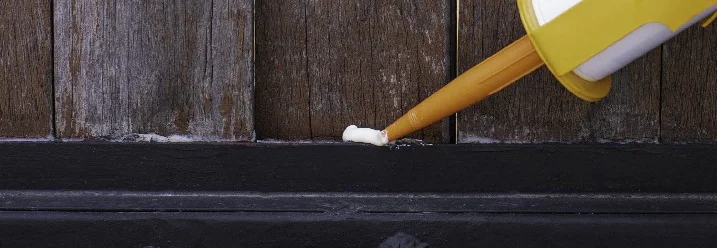 Dichtmasse wird auf Holz aufgetragen