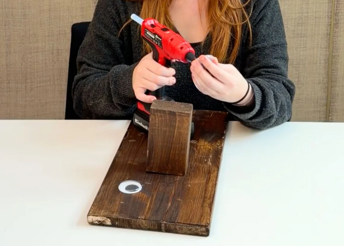 Ein Mensch benutzt eine Heißklebepistole für ein Bastelprojekt aus Holz.