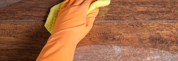 Hand reinigt Holzboden mit Schwamm