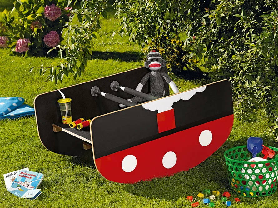 Rotes und schwarzes Spielzeugboot auf Gras