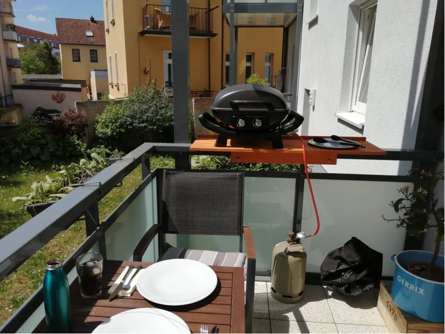 Balkon mit Gasgrill und gedecktem Tisch