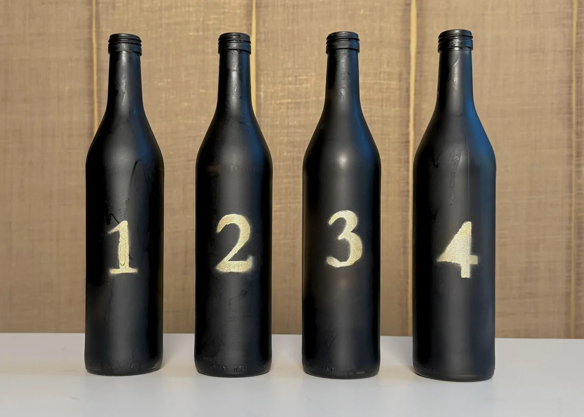 Vier schwarze Flaschen sind mit den Zahlen eins bis vier nummeriert.