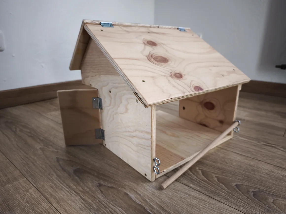 Ein kleiner Holzstall für Kinderspielzeug auf einem Holzboden.