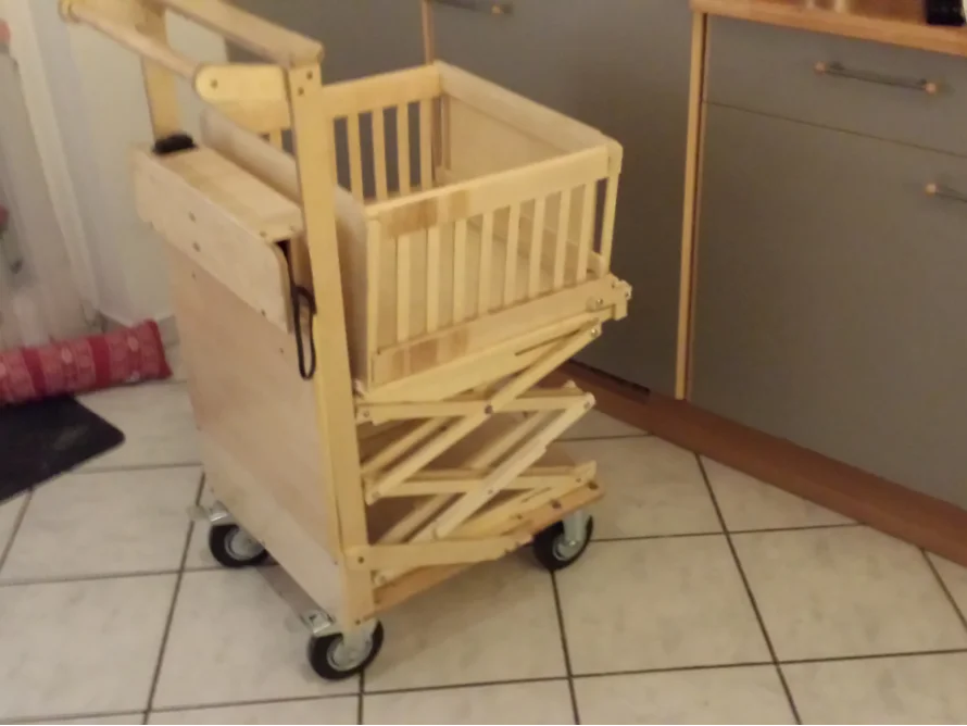 Ein höhenverstellbarer Beistelltisch aus Holz mit vier Rollen und einem Geländer.
