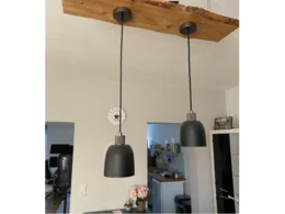 Zwei schwarze Hängelampen an Holzbalken