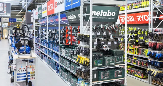 Ein langer Gang in einem Baumarkt mit Regalen voller Elektrowerkzeuge.