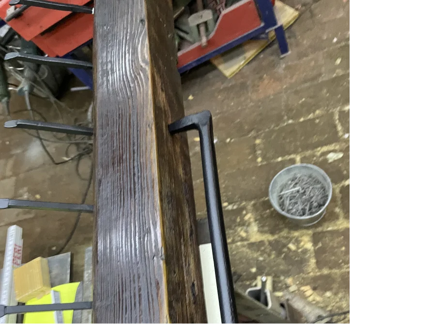 Schwarzes Metallgestell an Holzbalken