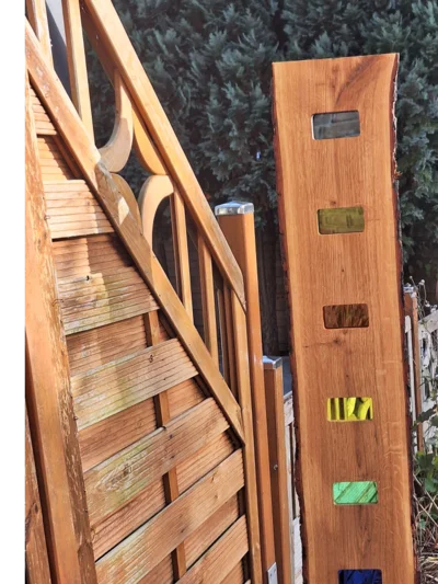Holzbrett mit Glaseinsätzen an Gartenzaun
