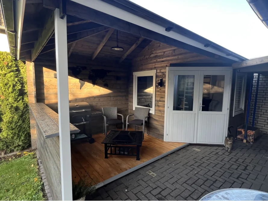 Überdachte Terrasse mit Grill und Sitzgelegenheiten