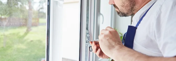 Person repariert Fenster mit Schraubendreher