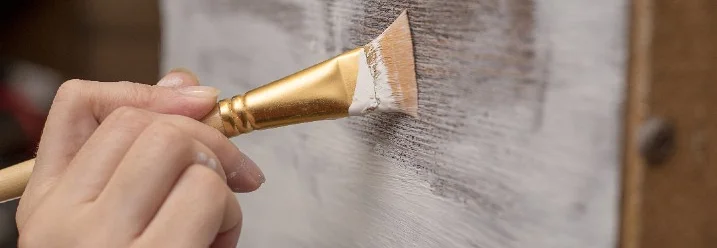 Hand streicht Kreidefarbe auf Holz
