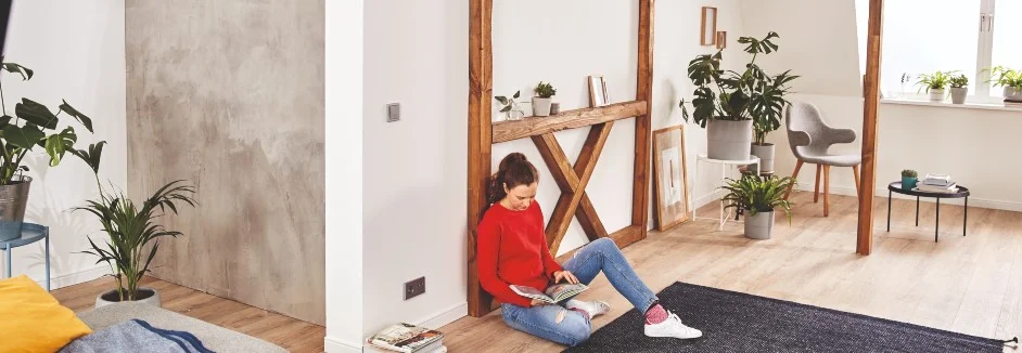 Person liest in einem Zimmer vor einer Fake-Fachwerk-Befestigung an der Wand