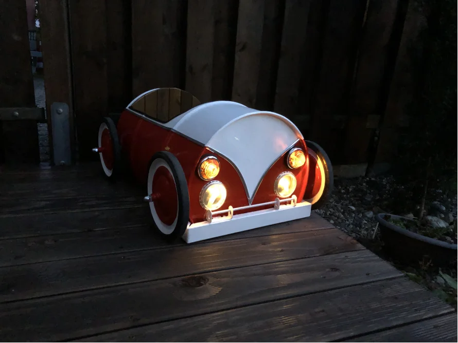 Rotes und weißes Spielzeugauto mit eingeschalteten Scheinwerfern