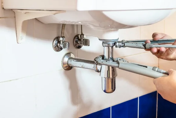 Person repariert Siphon mit Rohrzange